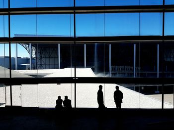 Silhouette people standing against window in city