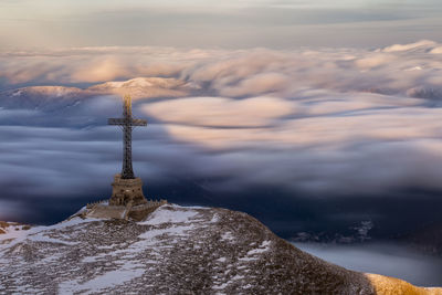 Religious cross on mountain by cloudscape