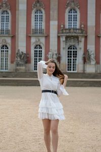 Full length portrait of woman standing against building