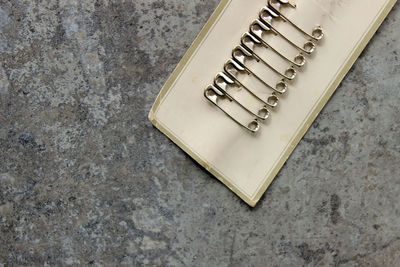 High angle view of safety pins attached in paper on floor
