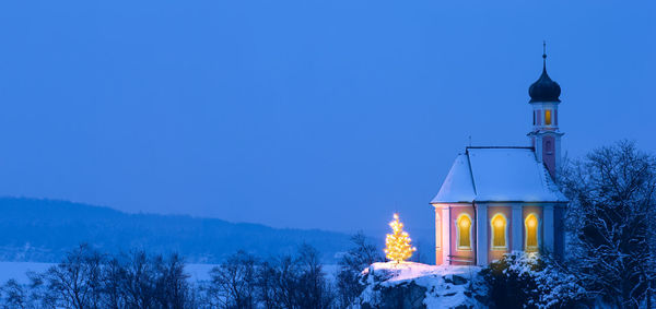 Illuminated building against sky during winter