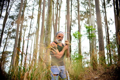 Man standing by tree trunk in eucalyptus forest