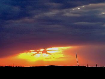 Silhouette landscape against dramatic sky during sunset