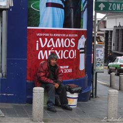Full length portrait of man sitting on street