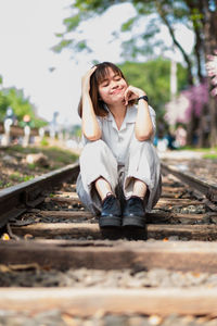 Woman sitting on railroad track