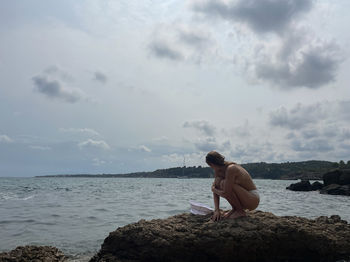 Woman sitting on the rock at the beach