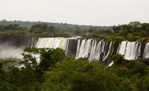 Scenic view of waterfall in forest against sky
