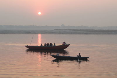 Boat sailing in sea at sunset