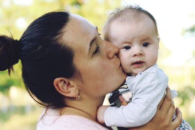 Close-up of mother kissing baby girl outdoors