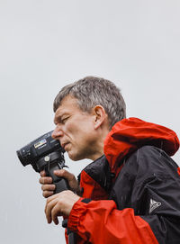 Side view of man photographing against gray background