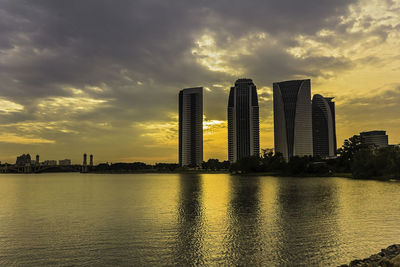 Scenic view of river by buildings against sky during sunset