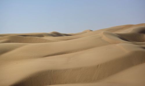 Sand dunes in desert against clear sky