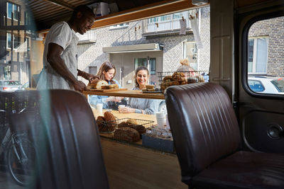 Mid adult salesman selling fresh bread to customers at food truck