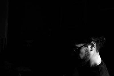 Close-up of young man looking away in darkroom