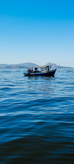 Boat sailing in sea against clear blue sky