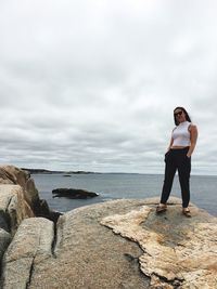 Full length of woman standing on rock against sea