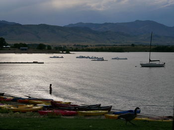 Boats moored on sea by mountains against sky