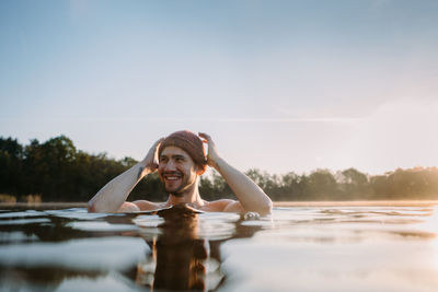 Young man soaks in the winter lake at morning. male person taking care of his health