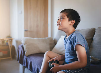 Child playing game online at home, young boy siting sofa having fun and relaxing on  weekend