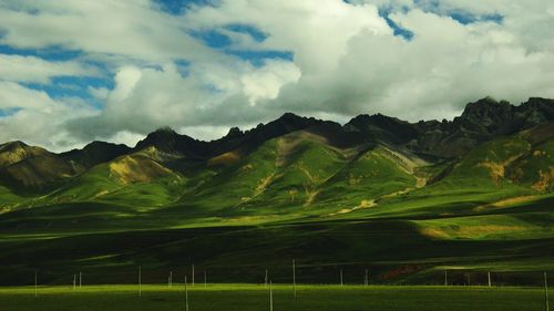 Panoramic view of green landscape and mountains against sky