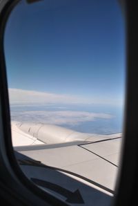 Close-up of airplane wing over sea seen through window