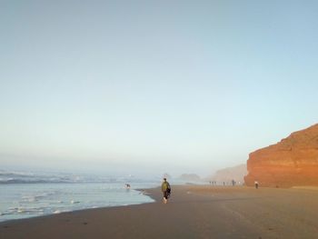 People on beach against clear sky