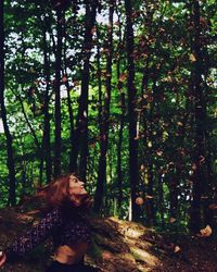 Woman standing by trees in forest