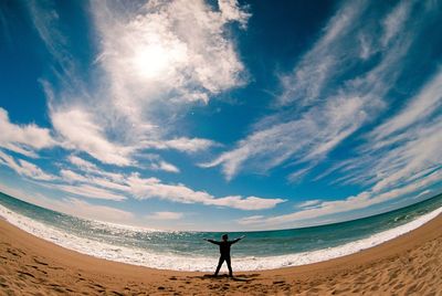 Rear view of man standing on beach against sky