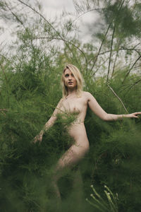 Young woman standing by tree on field