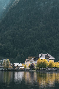 Houses by lake and buildings against mountain