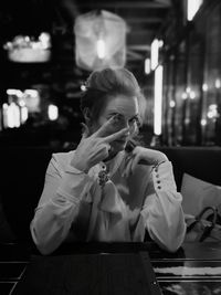 Portrait of woman showing peace sign while sitting in restaurant