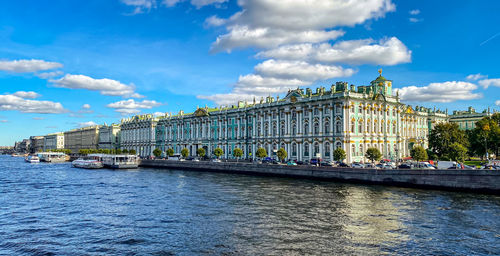 View of buildings at waterfront against cloudy sky