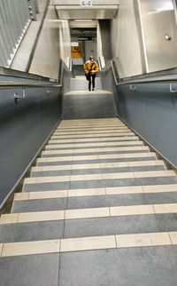 Rear view of man walking on staircase in building