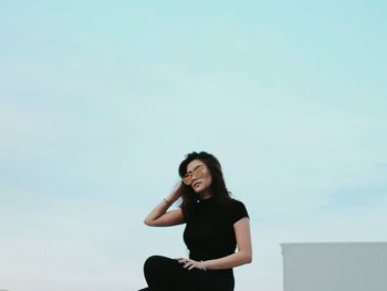 Low angle view of woman in sunglasses against clear sky