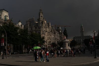 People on street against buildings in city