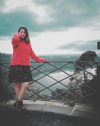 Woman standing by railing against sky