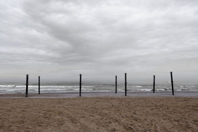 Wooden posts on beach against sky