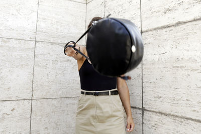 Rear view of woman standing on footpath against wall