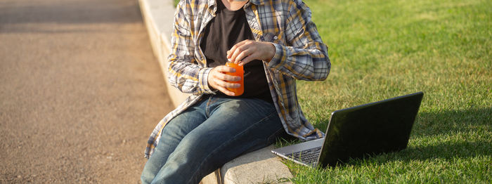 Low section of woman using laptop while sitting on field