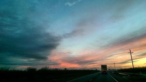 Empty road against cloudy sky at sunset