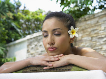 Close-up of young woman with eyes closed against trees