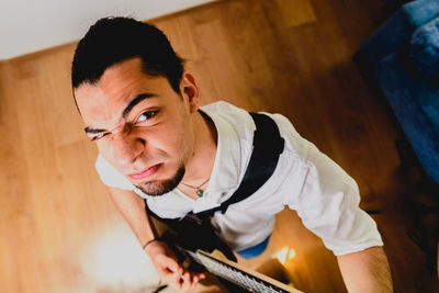 High angle portrait of man playing guitar at home