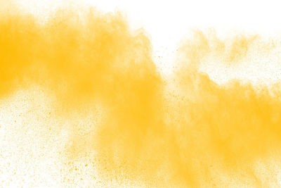 Defocused image of yellow powder paint against white background