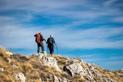 Low angle view of people walking on mountain against sky