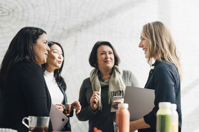 Female colleagues listening to businesswoman in meeting at conference event