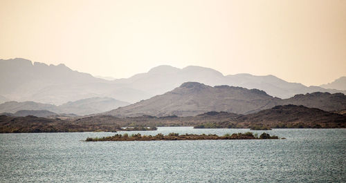 Scenic view of sea and mountains against clear sky