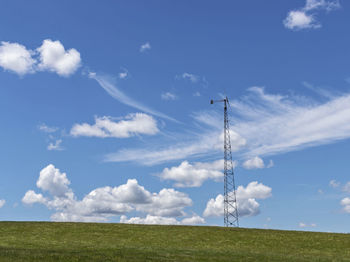 Windmill in green field with bright blue sky on summer day in maine.