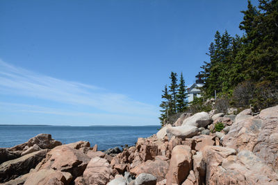 Rocks by sea against blue sky