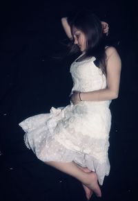 Young woman standing against black background