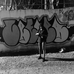 Full length of man standing by graffiti on wall